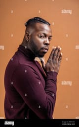 black-man-with-expressive-eyes-looking-at-camera-in-studio-shot-against-brown-background-2FMNN59