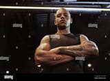 low-angle-shot-of-a-handsome-african-male-sportsman-looking-confidently-to-the-camera-with-arms-crossed-fierce-muscular-athletic-man-at-the-gym-2E1A2TP