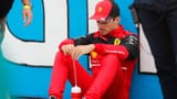 charles-leclerc-sitting-on-the-ground-against-the-pit-wall-planetf1