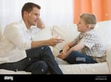 father-talking-to-son-on-sofa-B27R93