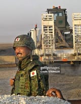 a-japanese-soldier-flashes-a-smile-as-a-truck-carrying-military-vehicles-leaves-his-base-in-the
