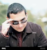 portrait-of-a-young-man-peeking-over-sunglasses-2EM52GB