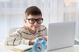 smart-nerd-kid-boy-glasses-ear-sitting-his-desk-home-using-laptop-computer_292052-2198[1]