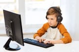 51334289-leisure-education-children-technology-and-people-concept-boy-with-computer-and-headphones-typing-on