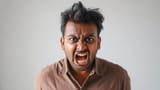 angry-young-man-with-wild-hair-yelling-in-brown-shirt-posing-for-studio-portrait-with-white-background-photo