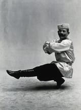 1280px-A_man,_in_a_satin_tunic_and_fur_hat,_dancing_a__Cossack__measure_in_a_studio_setting._Photograph,_ca.1899-1908