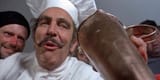 theatre-of-blood-vincent-price-in-a-white-chefs-hat-and-uniform-staring-down-while-shoving-food-down-a-victims-throat