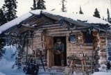 Image-w-cred-cap_-1200w_-Proenneke-Cabin-page_-Proenneke-in-doorway_2