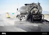 a-black-tanker-truck-spraying-tar-to-resurface-a-road-in-the-desert-K3KNA3