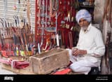 a-merchant-sells-knives-scissors-and-other-goods-from-his-tiny-stall-AM05PX
