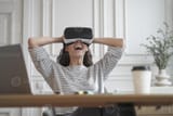 amazed-woman-office-employee-in-vr-glasses-laughing-and-leaning-back-in-chair-with-hands-behind-head-photo