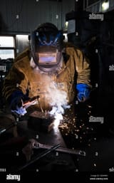 blacksmith-in-welding-mask-welding-metal-in-workshop-KD0HMY