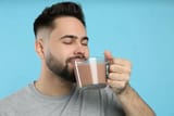 young-man-drinking-chocolate-milk-light-blue-background-young-man-drinking-chocolate-milk-light-blue-background-214103100