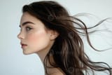 profile-shot-of-a-beautiful-young-brunette-with-wind-swept-hair-against-a-white-backdrop-photo