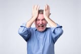 furious-senior-man-holding-his-head-in-hands-and-screaming