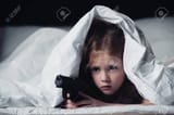 130204465-frightened-child-holding-gun-while-hiding-under-blanket-isolated-on-black