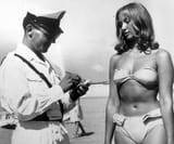 A police officer issuing a woman a ticket for wearing a bikini on an Italian beach, 1957