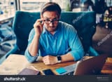 stock-photo-portrait-of-handsome-proud-ceo-looking-through-glasses-sceptical-doubting-in-information-confident-723423157