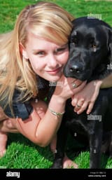 young-white-blond-woman-girl-with-hugging-her-black-labrador-puppy-BBJC1G