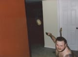 fat man with gun pointing at masked figure