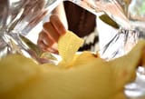womans-hand-picking-up-yellow-potato-chips-inside-a-bag-of-snacks