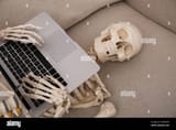 waiting-concept-human-skeleton-with-laptop-on-sofa-2XD4XCW