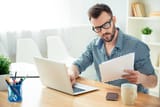 portrait-of-concentrated-businessman-in-glasses-with-laptop-reading-contract