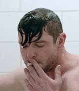 defeated-man-smoking-cigarette-in-shower