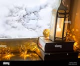 indoor-winter-background-with-candle-lantern-books-and-lights-on-frozen-H8N6EY