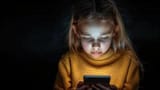 little-girl-in-yellow-sweater-looking-at-cell-phone-photo